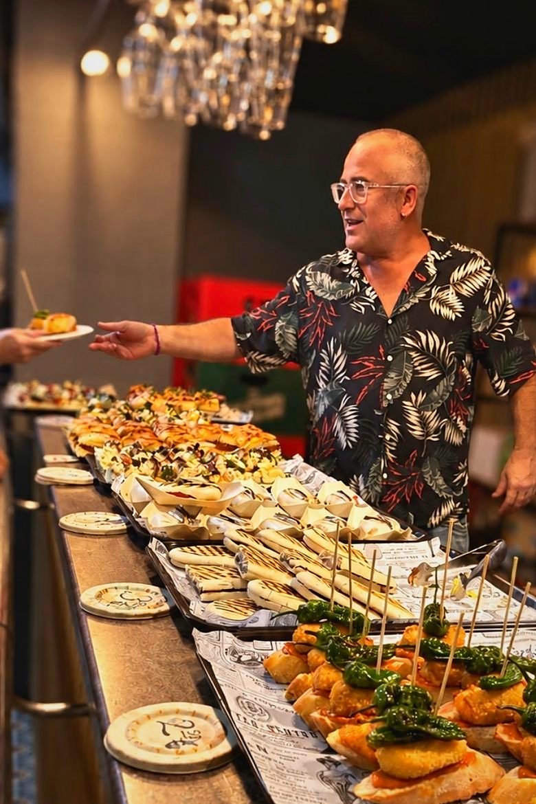 El Dani, amb camisa estampada, servint pintxos a la barra del Trampolí
