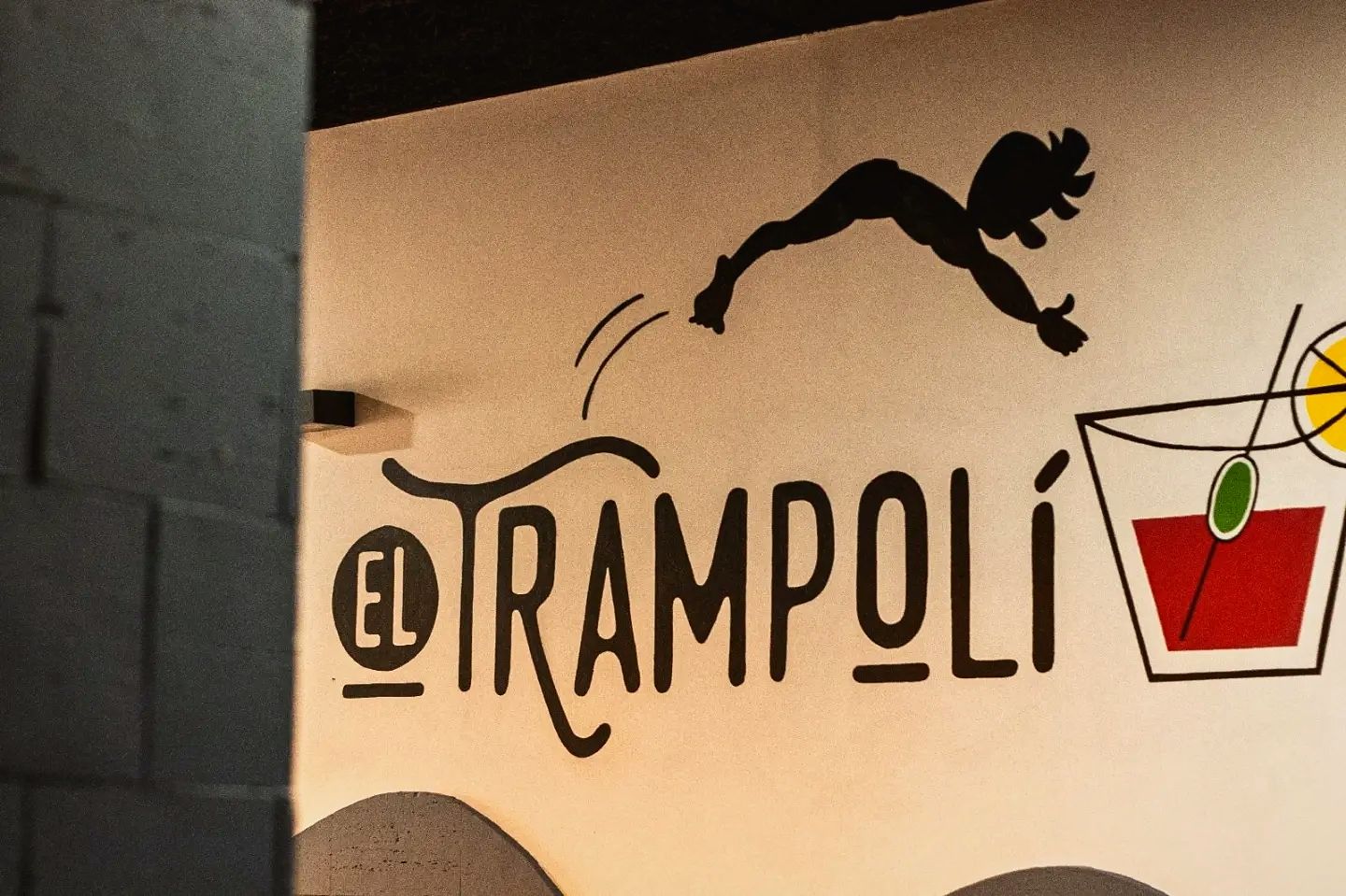 Mural a la paret del bar: un saltador es llança cap a un got de vermut amb oliva i llimona, al costat del nom El Trampolí
