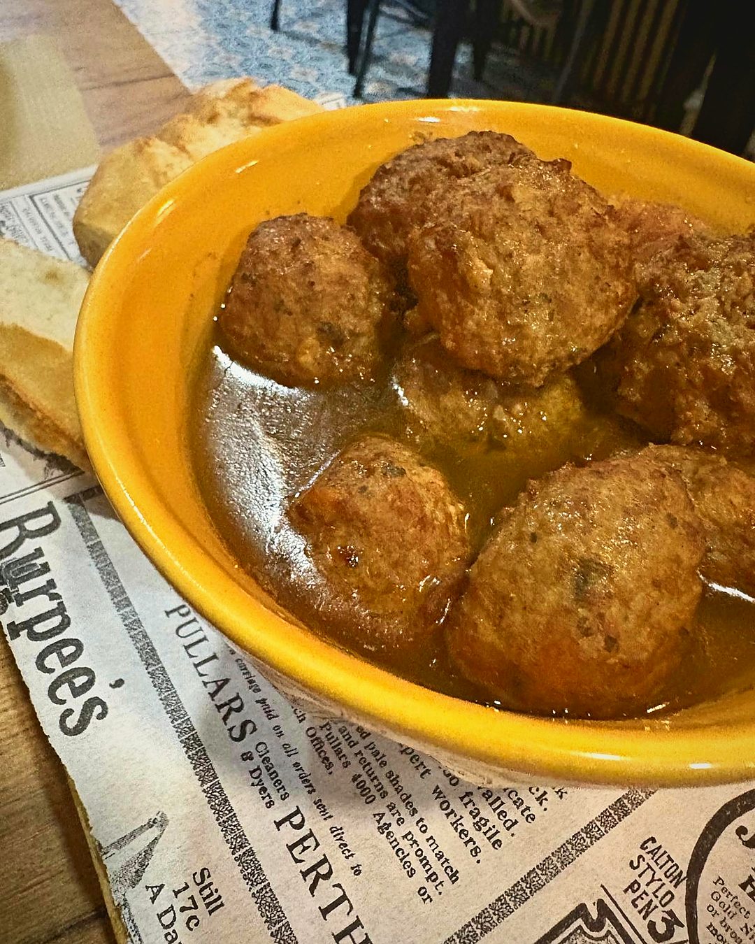 Mandonguilles amb ceps i el seu suc en un bol groc, amb pa